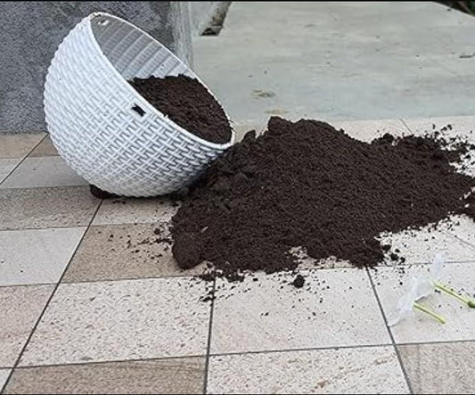 White woven planter tipped over spilling dark organic vermicompost fertilizer on tiled patio floor