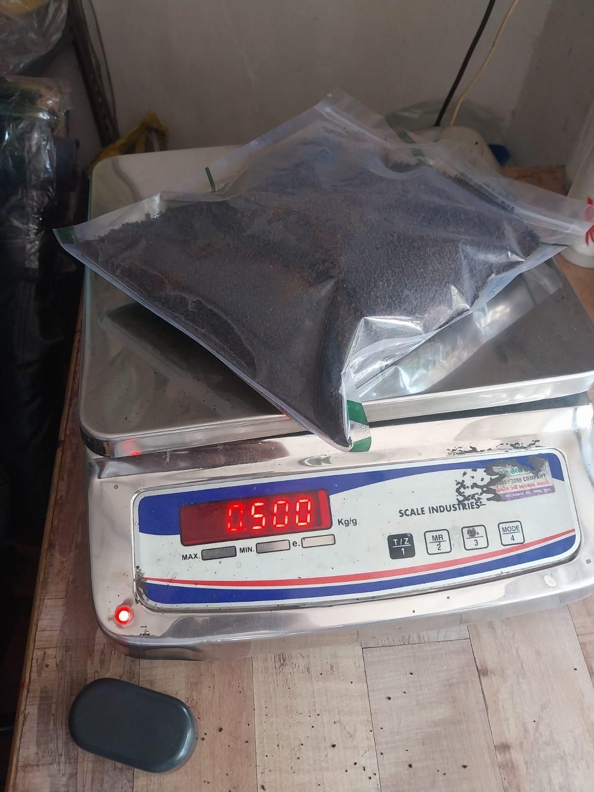Clear sealed bag of dark compost on a digital scale showing half kilogram organic vermicompost fertilizer