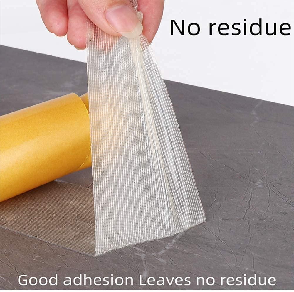 Hand peeling transparent mesh heavy duty carpet adhesive tape from floor next to yellow backing roll no residue