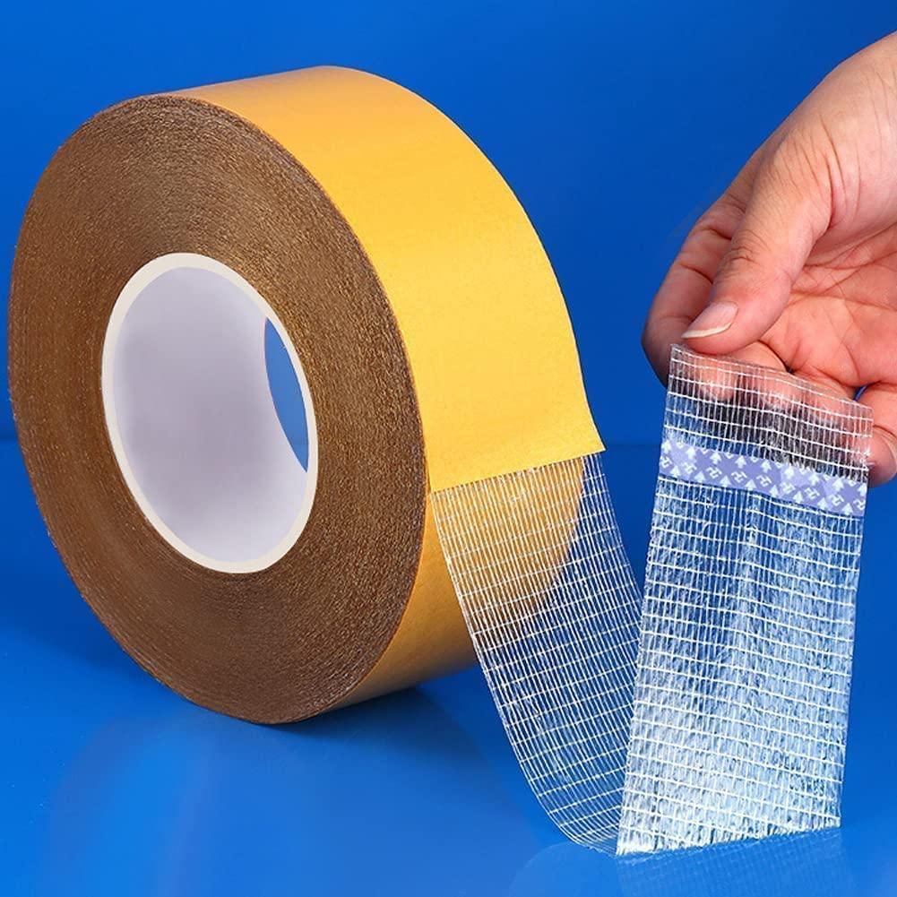 Roll of heavy duty carpet adhesive tape with yellow backing and clear fiberglass grid being peeled by hand on blue background