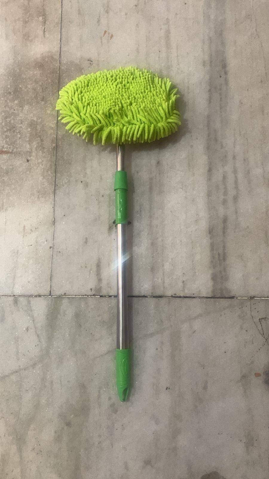 Green microfiber adjustable mop for outdoor use with extendable metal handle on tiled floor