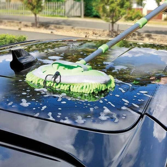 Adjustable mop for outdoor use cleaning soapy water from a black car roof on a sunny day