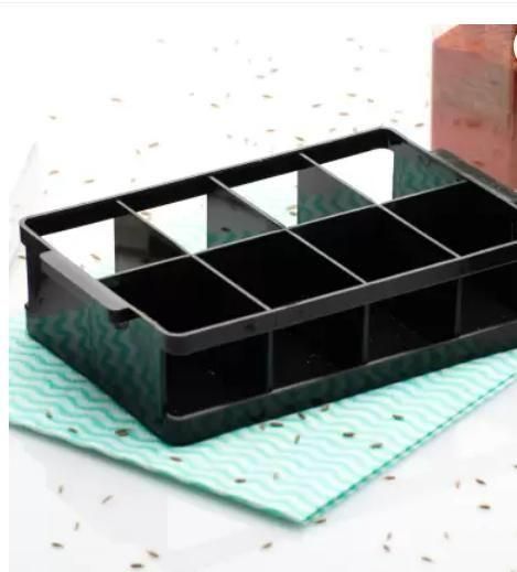 Black organizer tray with multiple compartments placed on a teal cloth for airtight spice jar set