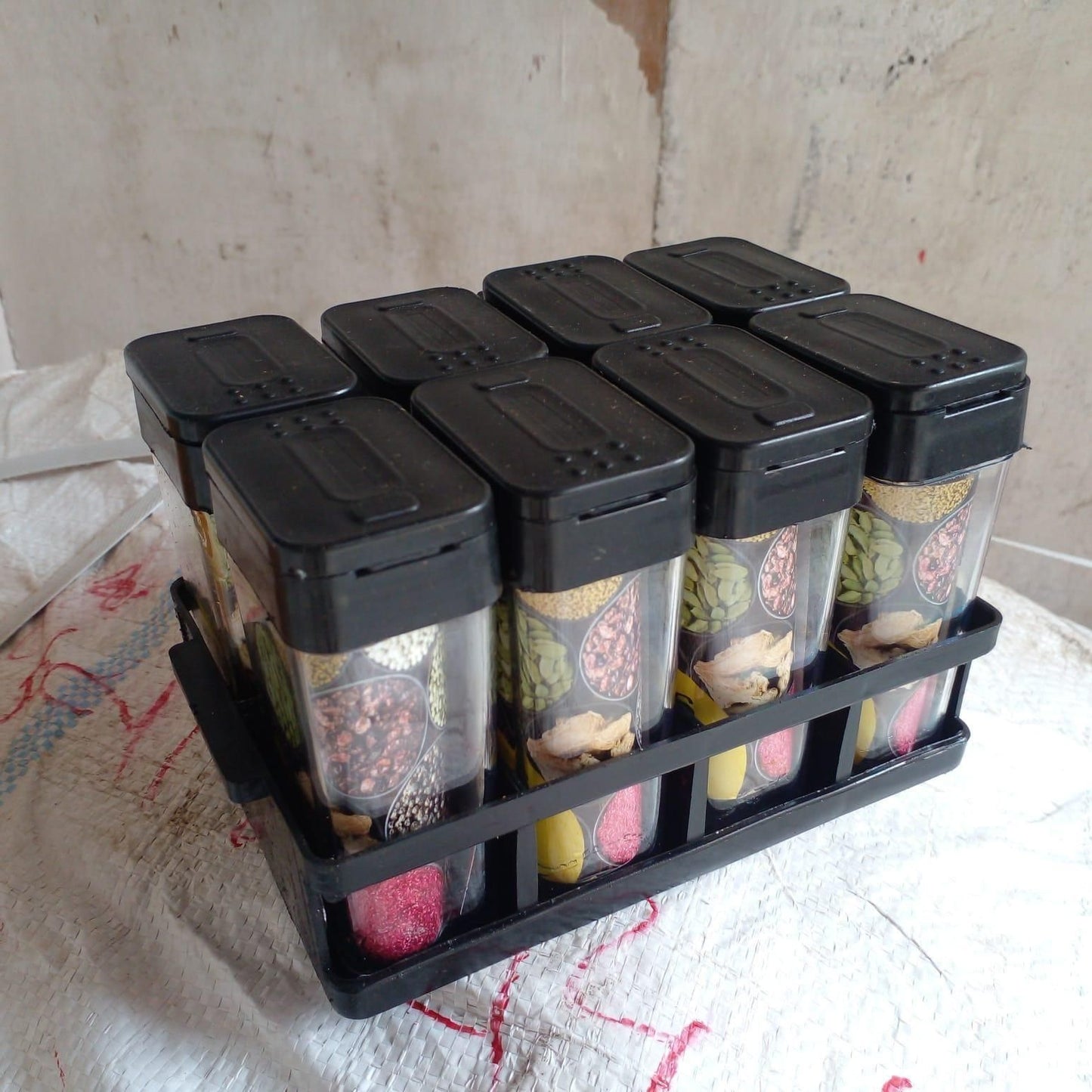 Airtight spice jar set with black lids and clear containers in a black rack for organized kitchen storage
