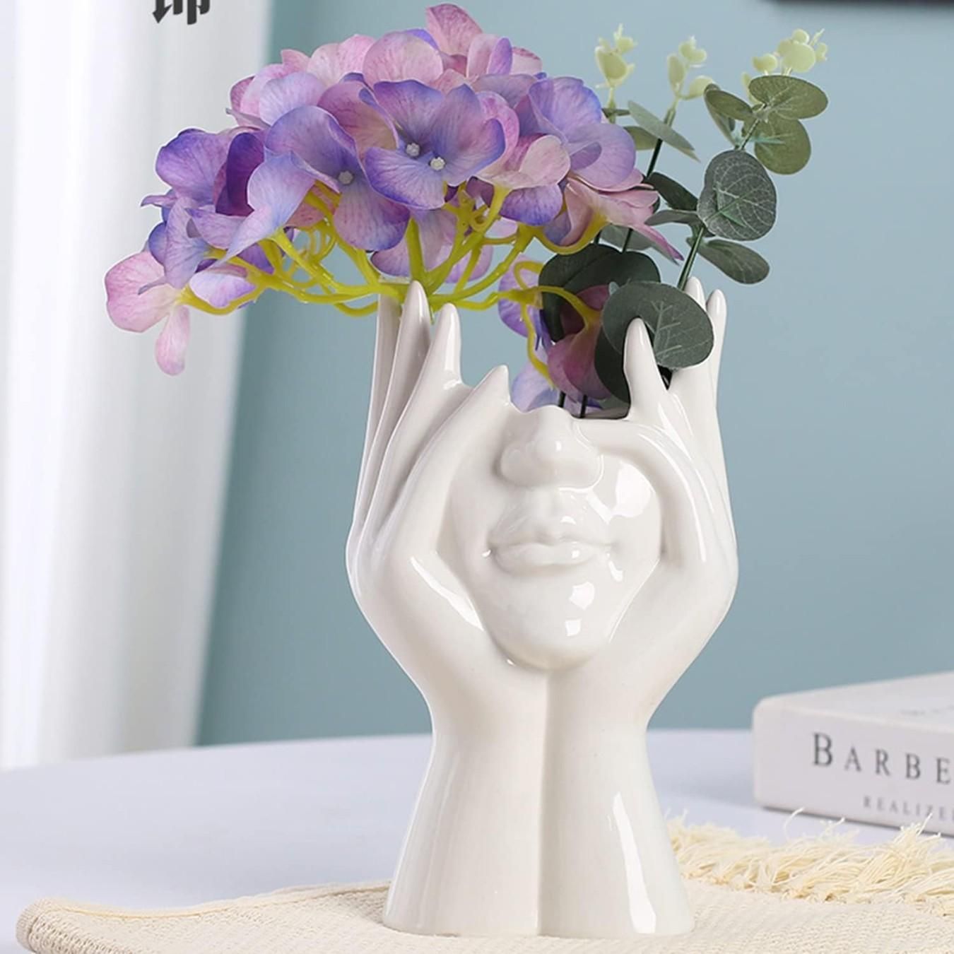 Artistic hand face vase for home decor featuring a white ceramic design with flowers