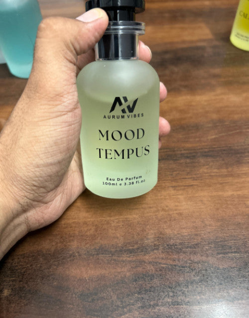 Hand holding Mood Tampus natural fragrance Eau De Parfum 100ml bottle on wooden surface