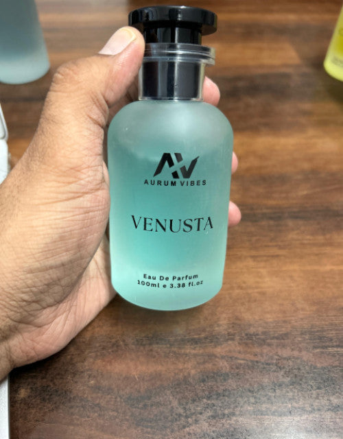 Hand holding Venusta perfume 100ml bottle by The Gir Farmer with frosted glass and black cap