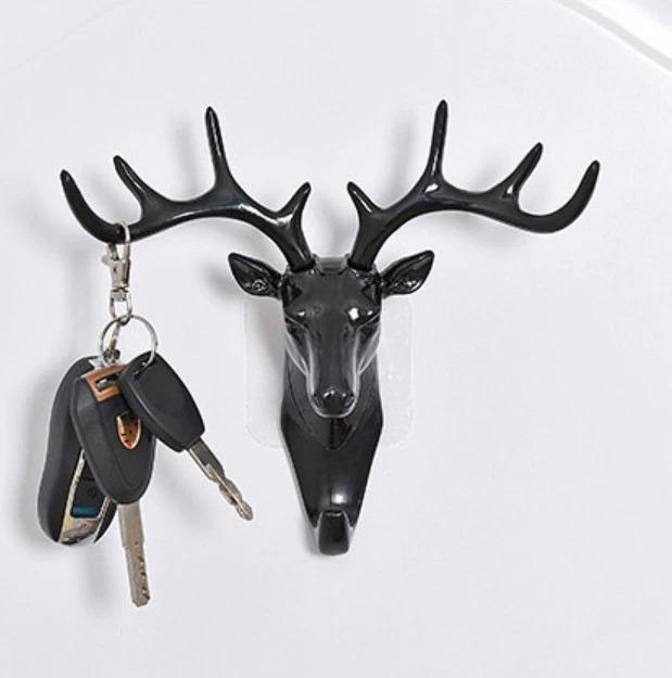 Black deer head shaped self adhesive coat hook holding keys on white wall