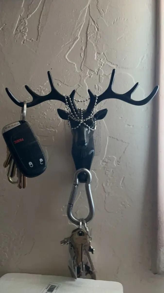 The Gir Farmer black deer head self adhesive coat hook holding keys and key fob on textured wall