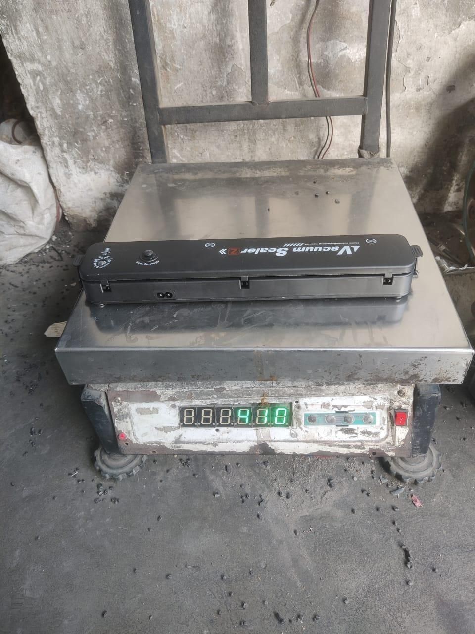 Multi-functional vacuum sealing machine placed on a digital weighing scale in an industrial setting