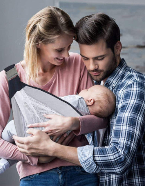 Dropdash breathable baby sling carrier in use, securely holding a sleeping baby between parents