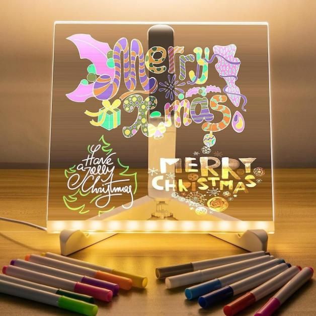Acrylic LED drawing panel with colorful Merry Christmas sketches and markers on wooden table light up drawing pad for kids