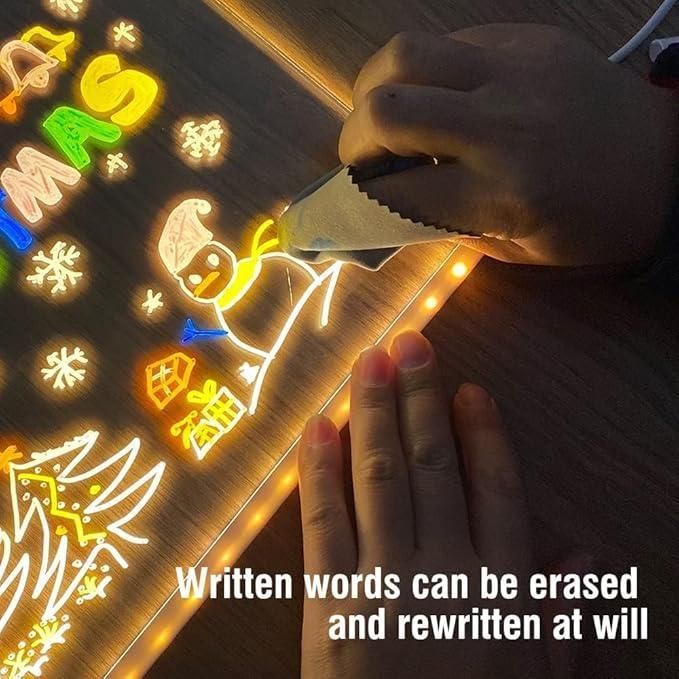 Child using pen on a light up drawing pad for kids showing glowing erasable Christmas snowman and tree
