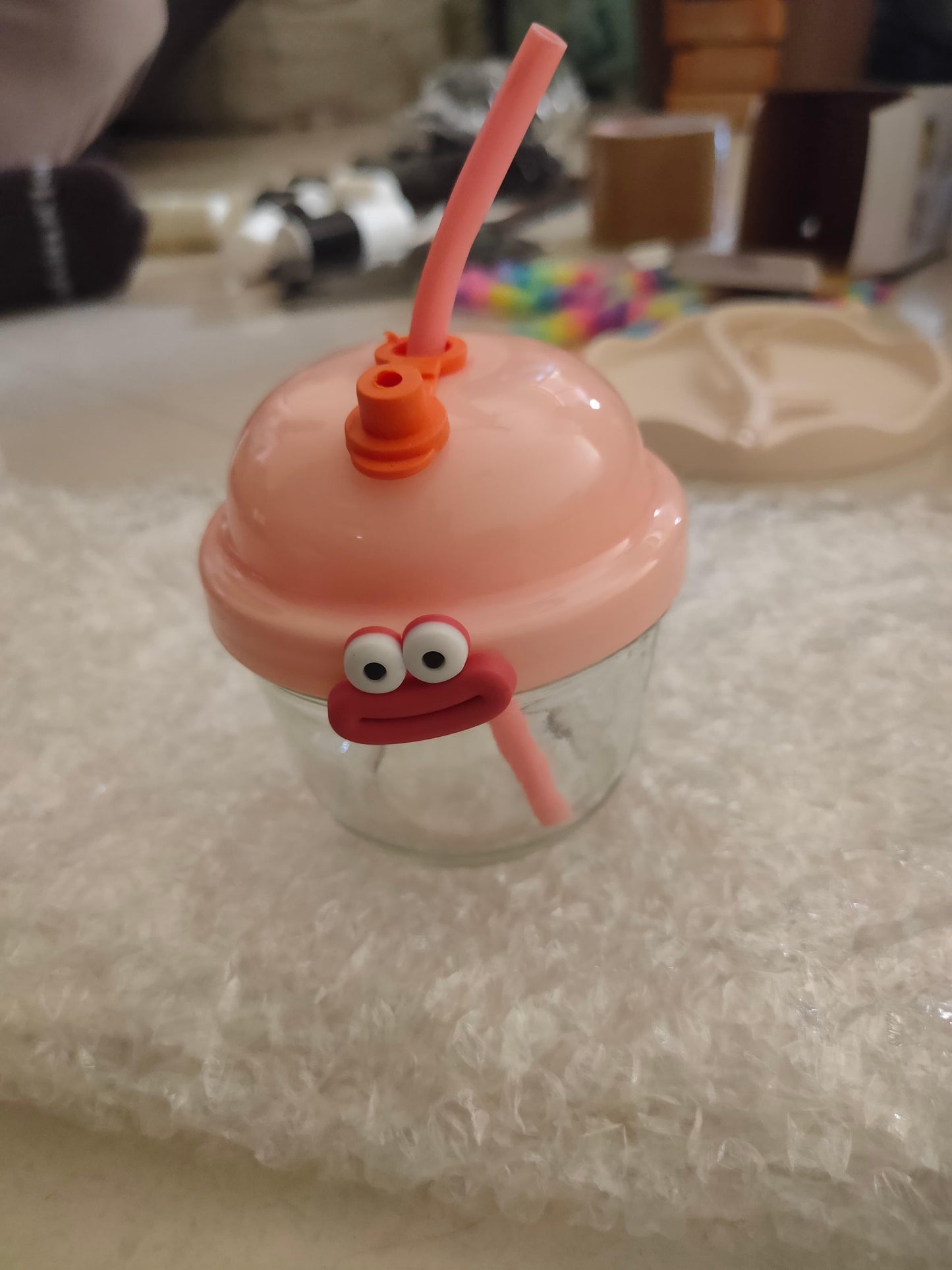 Cute cartoon glass cup for kids with a pink lid and straw featuring a cheerful character face