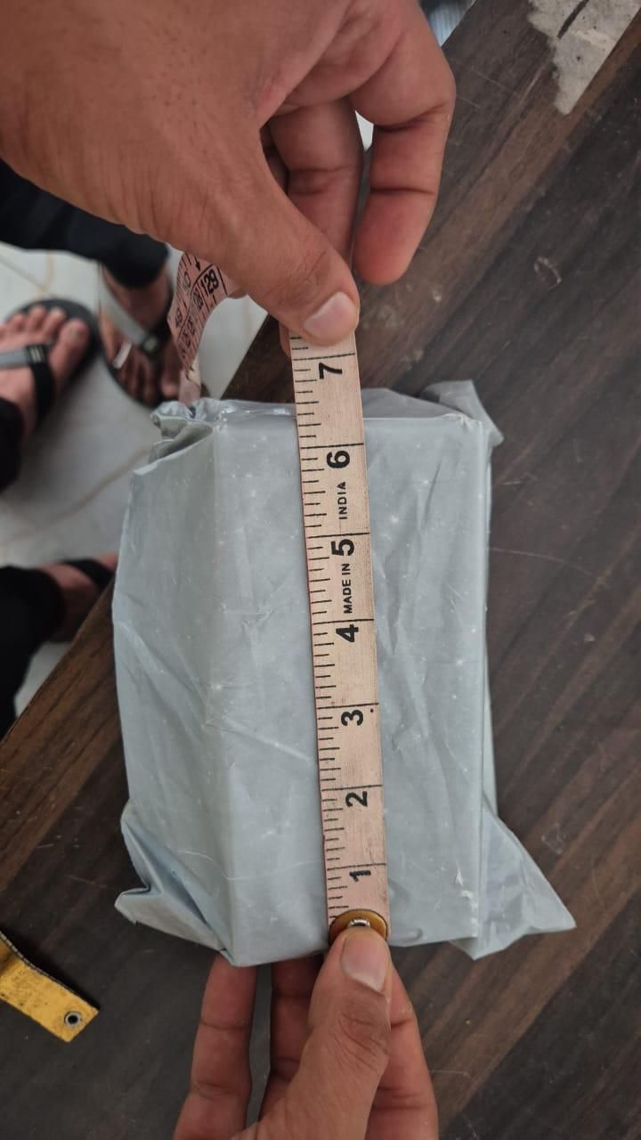Hands measuring a wrapped package with a ruler showing dimensions of aquarium water cleaner for freshwater and saltwater