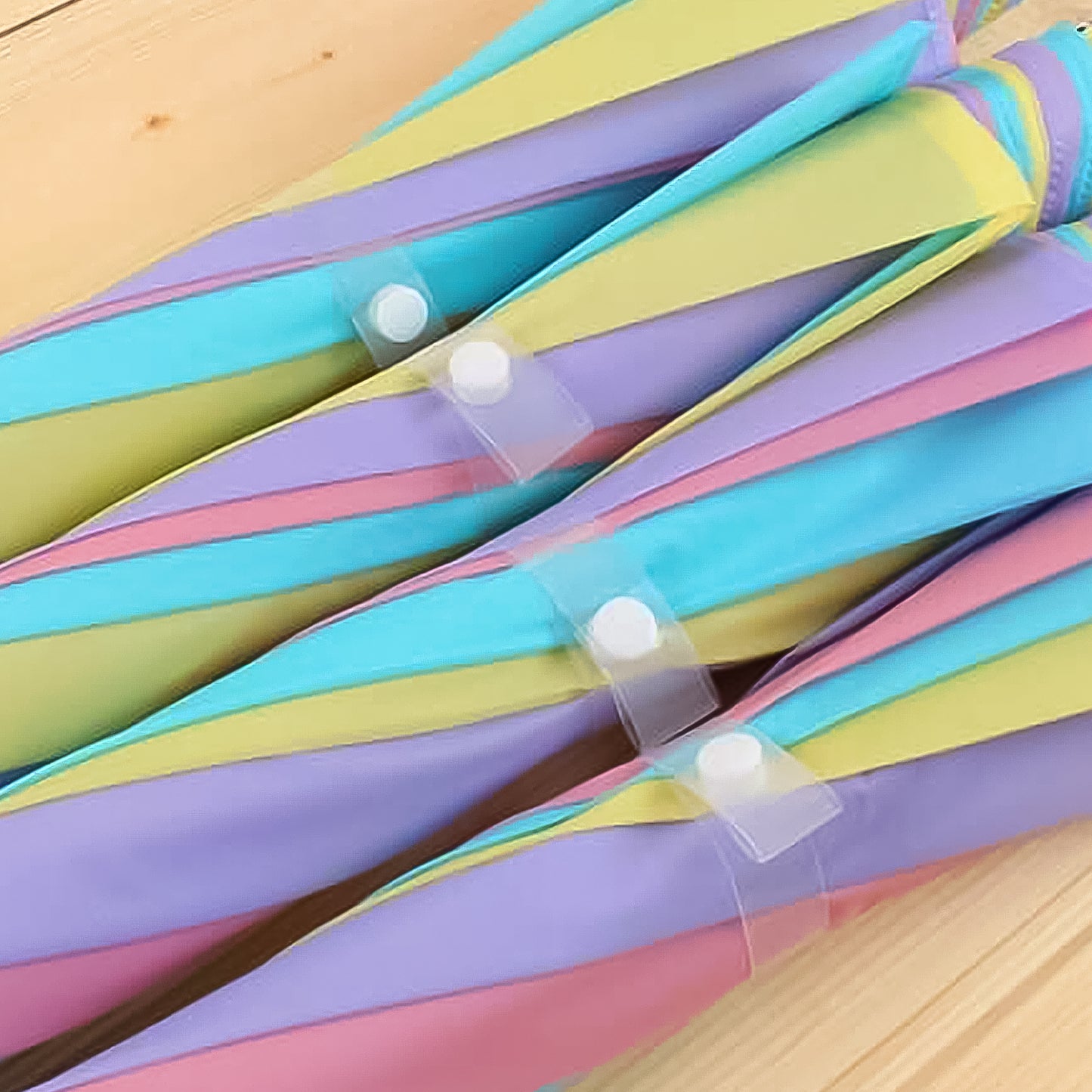 Folded colorful rainbow umbrella by Wukusy with pastel stripes on wooden surface for home improvement