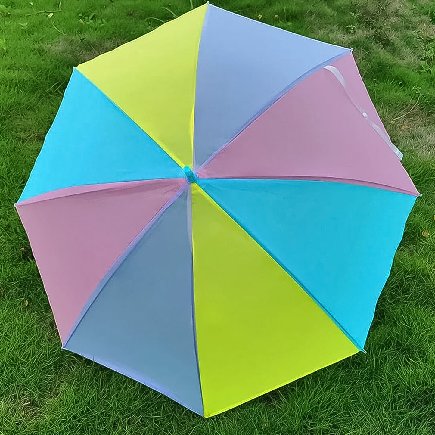 colorful rainbow umbrella with vibrant pastel panels open on green grass