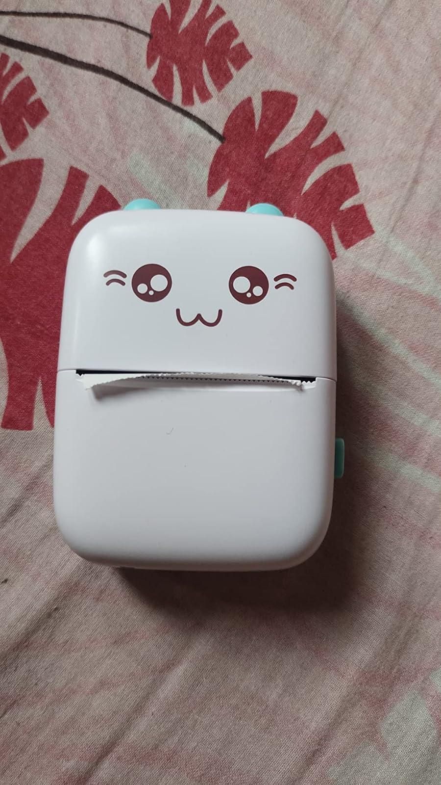 White cute inkless pocket printer with kawaii face design on fabric background