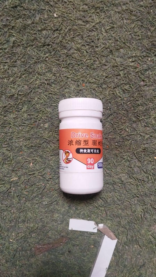 White bottle of natural snake repellent pellets by THE GIR FARMER on green textured surface