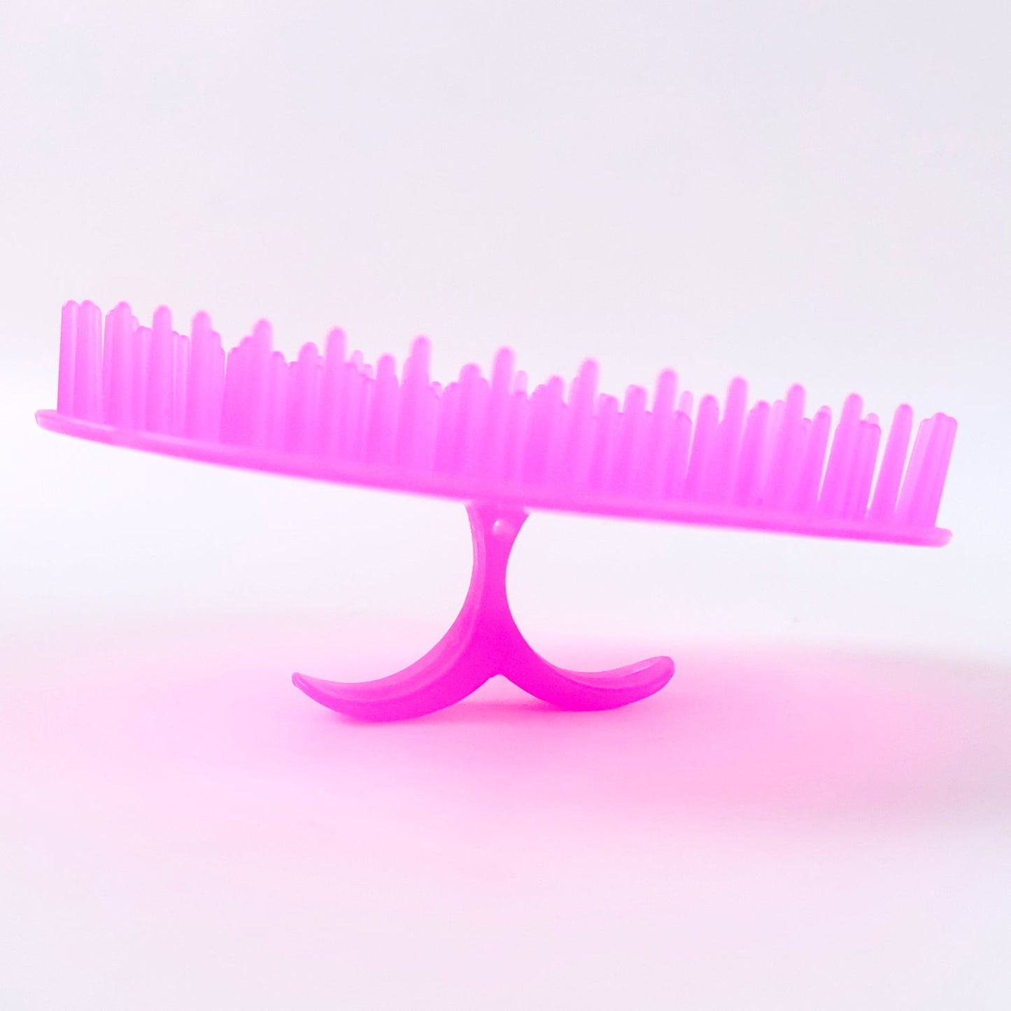 Ergonomic scalp massager brush in vibrant pink for soothing and stimulating the scalp