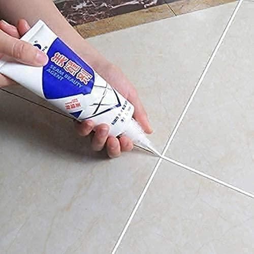Hand applying gap filler tube for home repair to tile grout lines for sealing and finishing