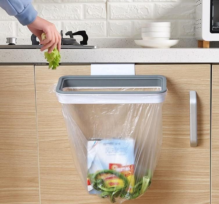 Attachable kitchen garbage bag holder hanging on cabinet door with kitchen waste inside