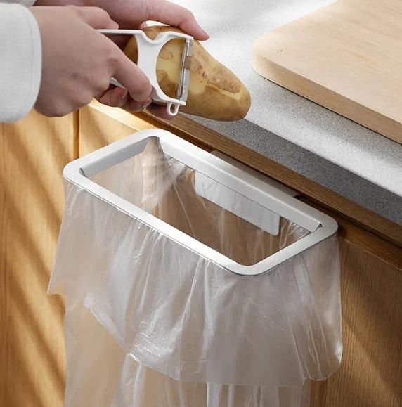 Attachable kitchen garbage bag holder fixed on cabinet with peeling potato over countertop