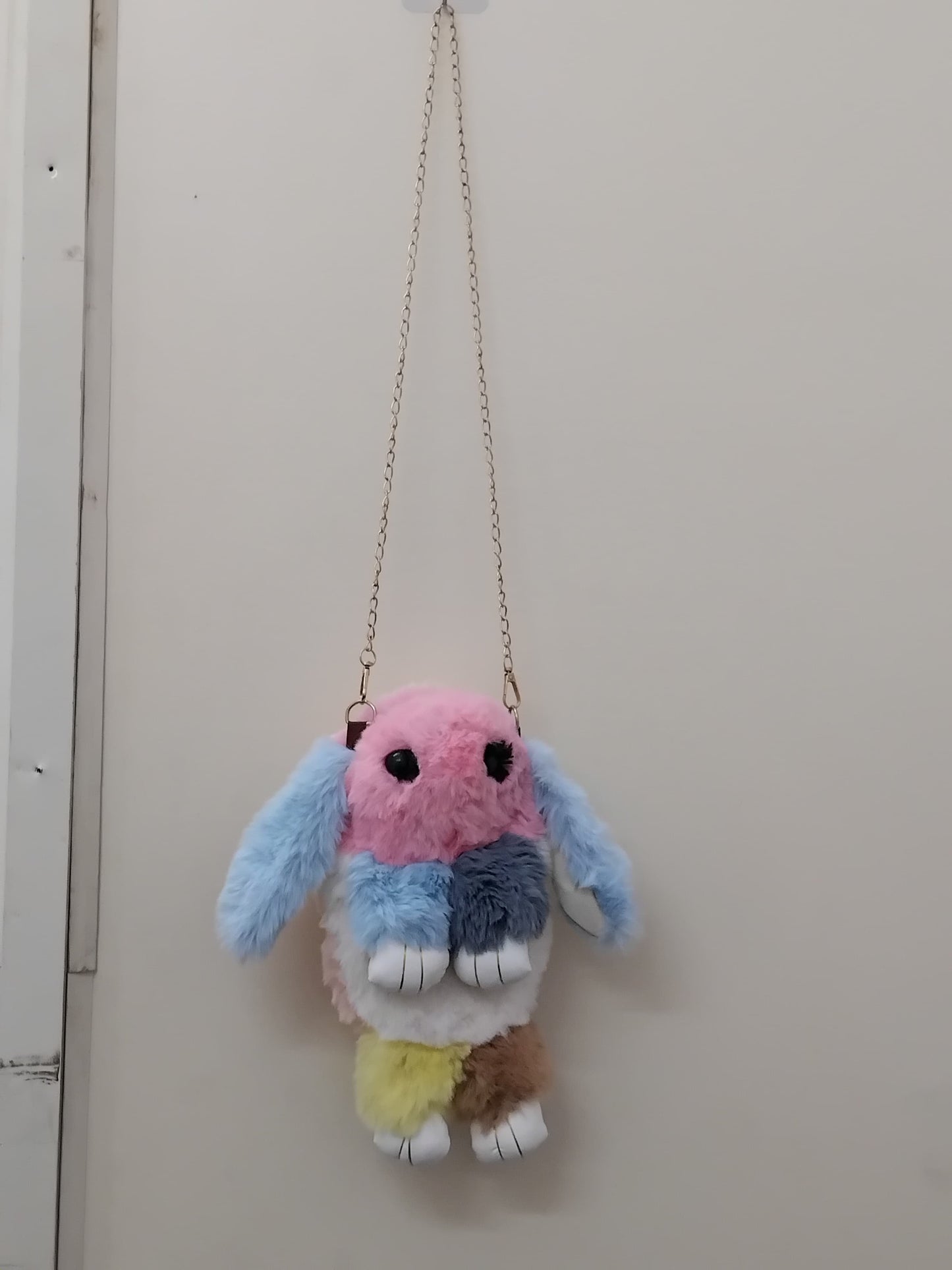 Girls bunny shaped sling bag with chain in pastel colors by THE GIR FARMER hanging on white wall