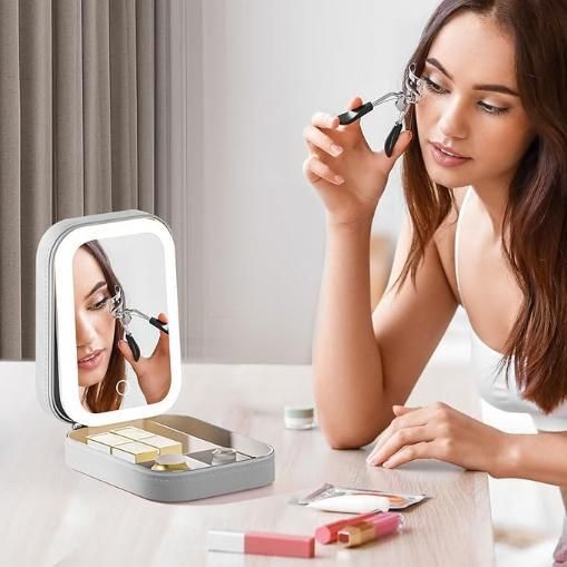 THE GIR FARMER lighted makeup mirror with storage tray woman using eyelash curler at vanity
