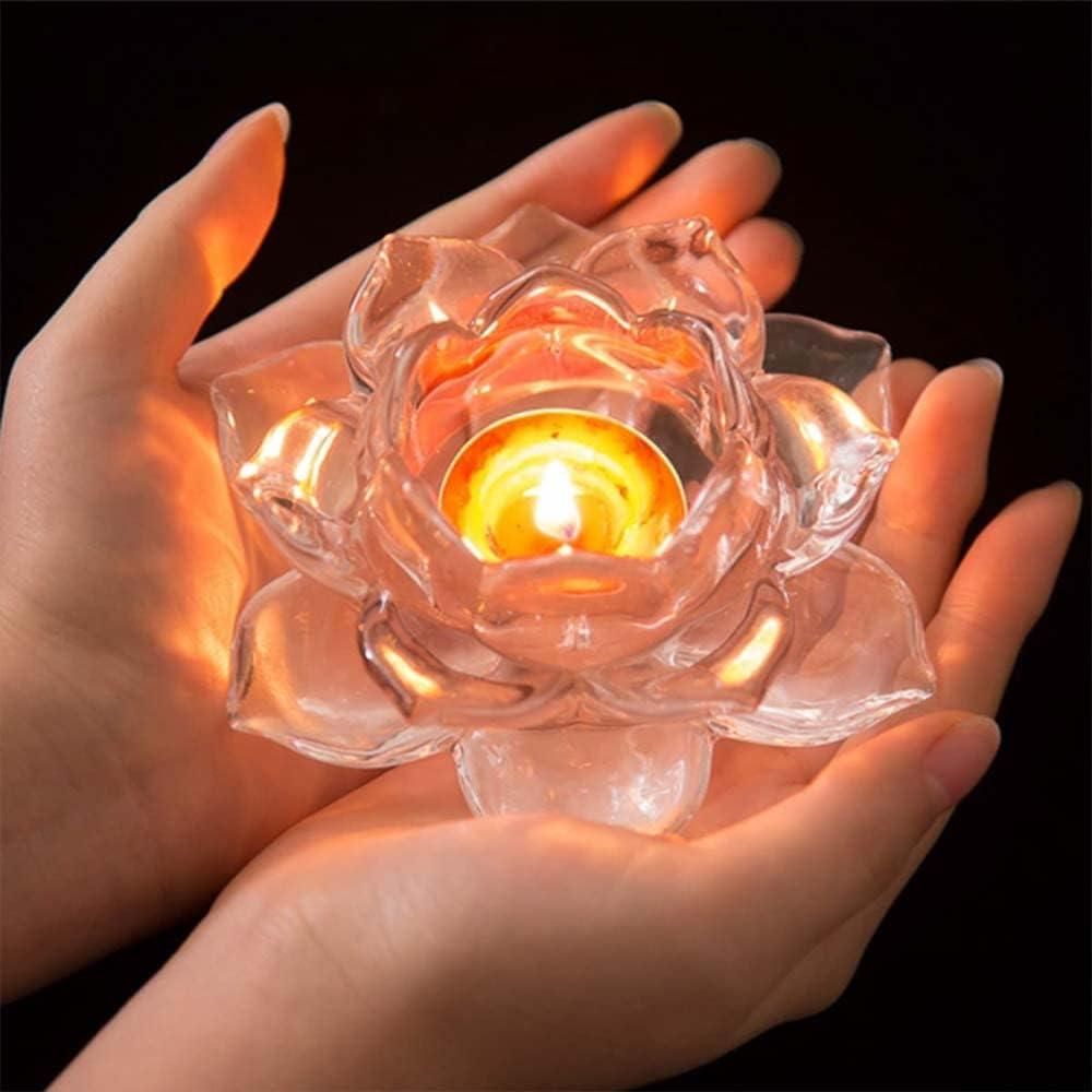 Hands holding a glowing glass lotus tea light holder with a lit candle inside