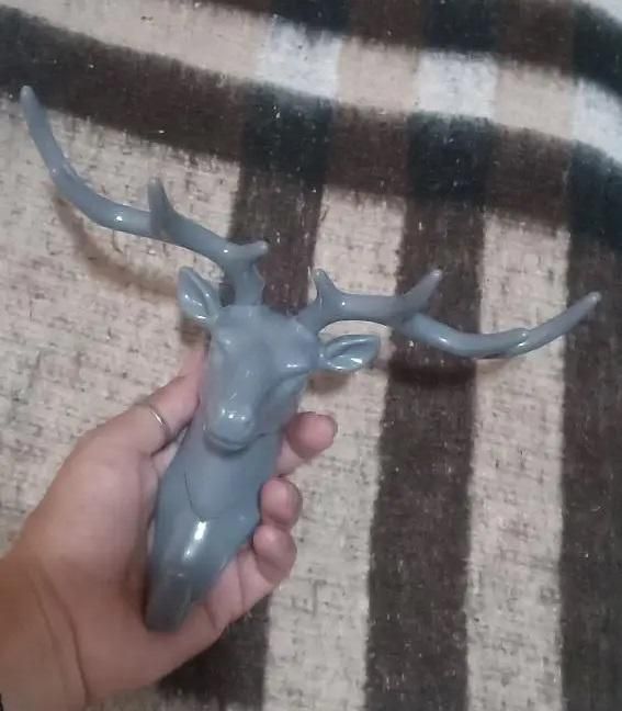 Gray deer head self adhesive coat hook with large antlers held in hand by The Gir Farmer