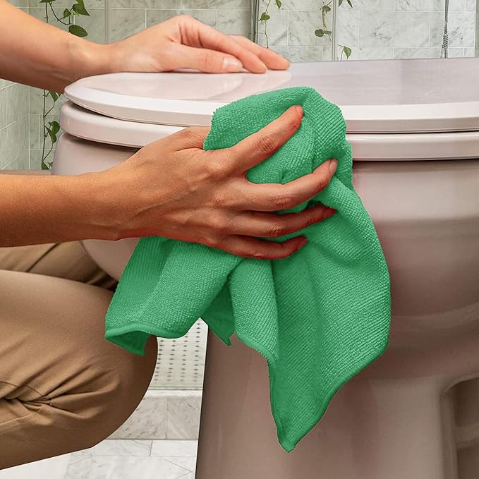 Green microfiber cloth for household cleaning used to wipe a toilet seat in a bathroom