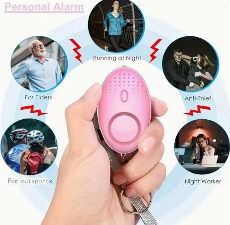 Pink emergency safety keyring personal alarm held in hand for protection against theft and during night activities