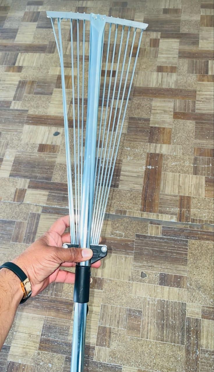 Hand holding adjustable metal leaf rake from THE GIR FARMER, the best tool for cleaning garden leaves