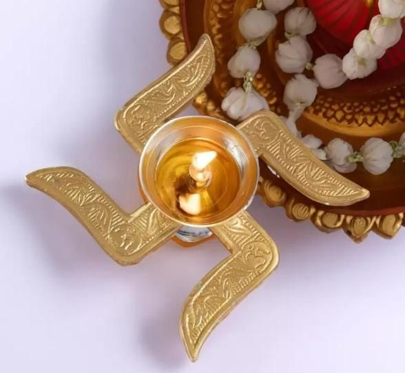 Top view of handcrafted puja brass diya with intricate design and burning wick for traditional worship