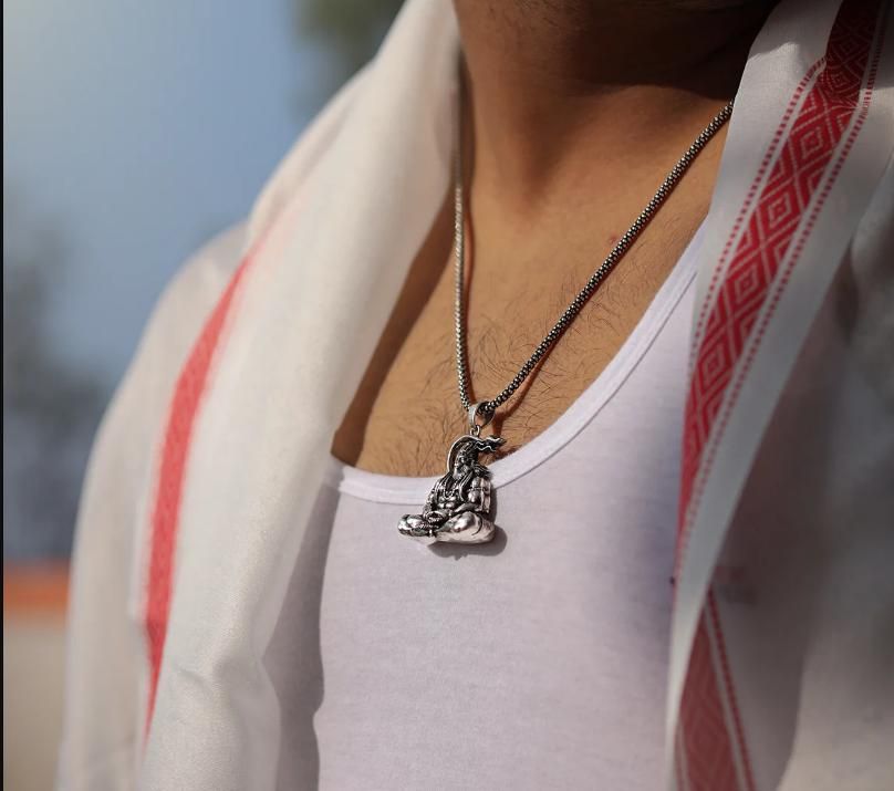 Hanuman silver locket hanging on a silver chain worn by a man in a traditional outfit