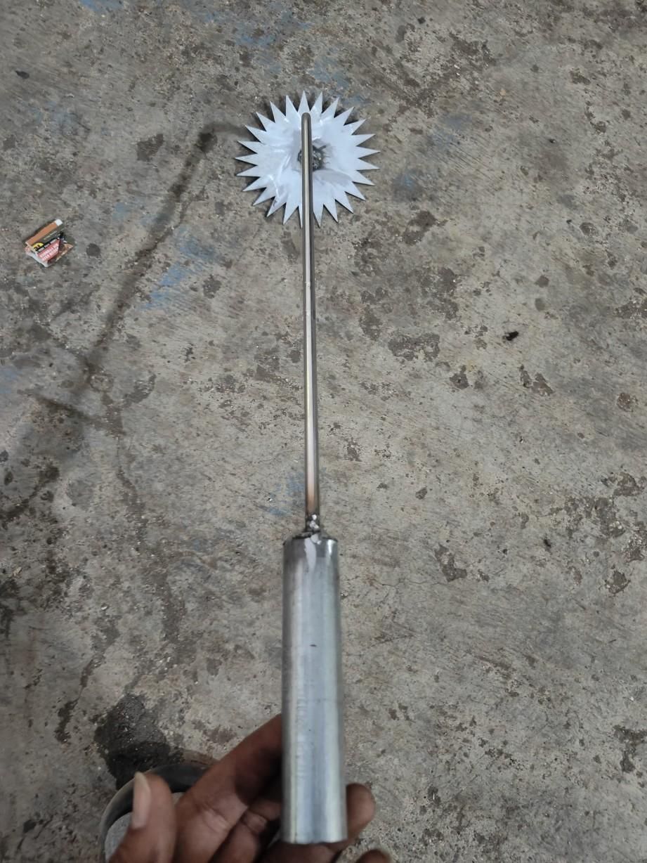 Heavy duty metal weed crusher with sharp rotating star-shaped blade and long handle for effective weed removal
