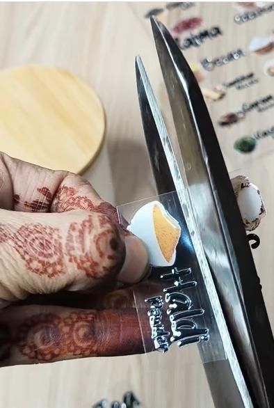 Person cutting a spice jar label set for kitchen with scissors showing a turmeric label and others in the background