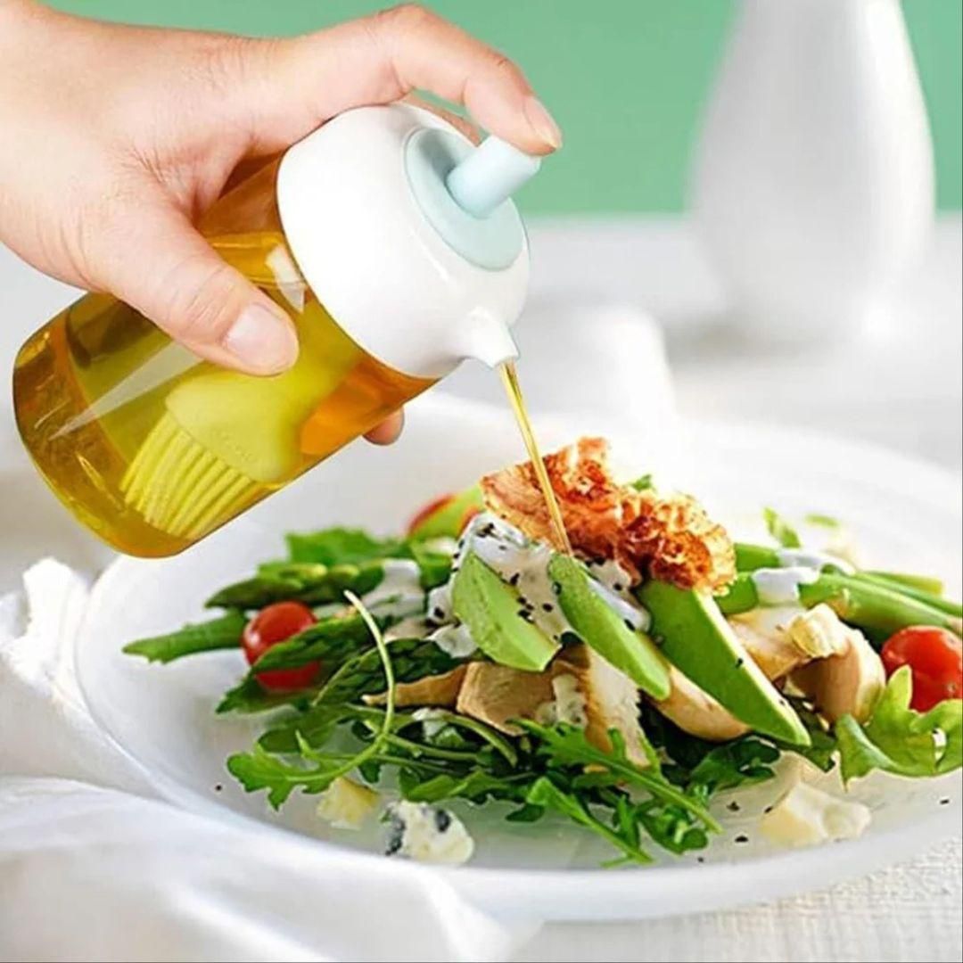 Hand pouring oil from a clear bottle onto fresh avocado salad oil dispenser for kitchen cooking