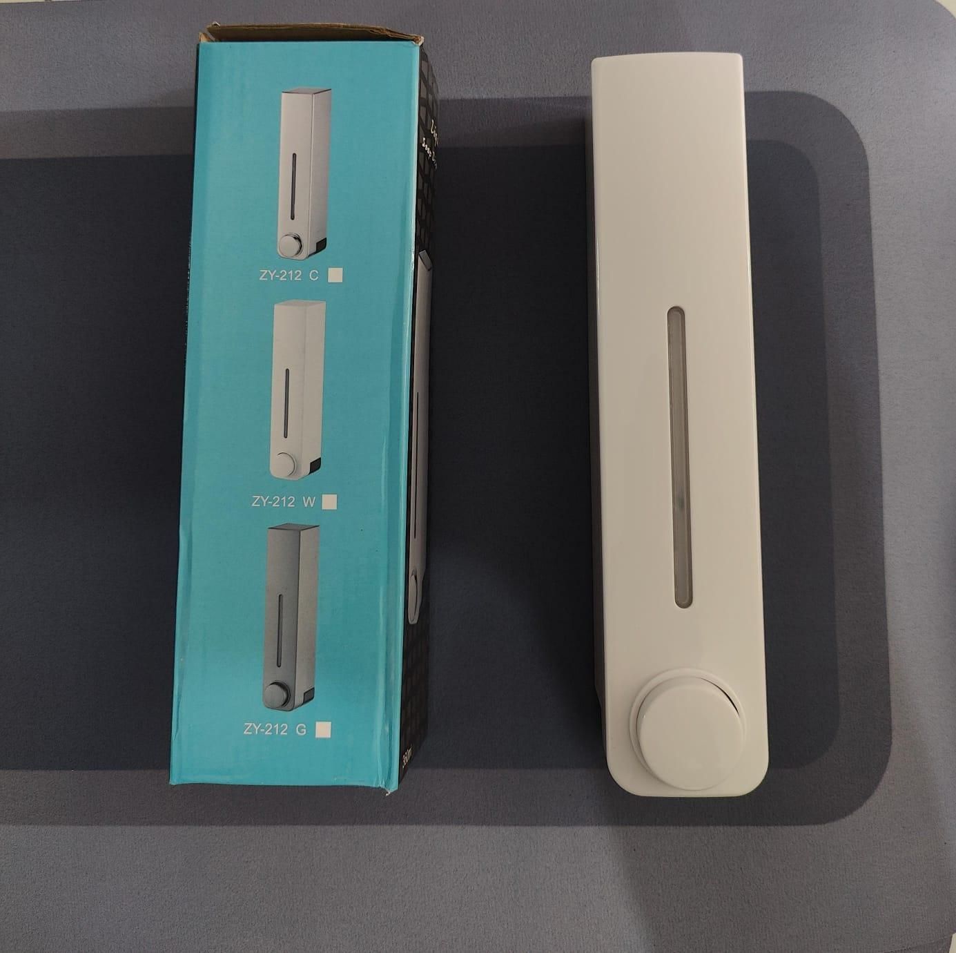 White wall mounted soap dispenser with clear level window and round push knob next to box