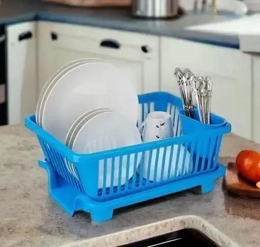 Blue compact plastic dish drainer with cutlery holder on kitchen countertop holding plates mugs and forks