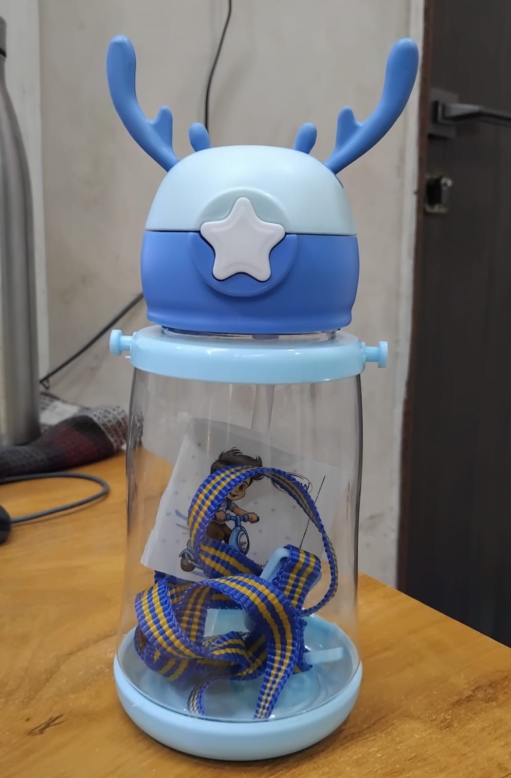 The Gir Farmer blue cartoon deer water bottle for kids with antler lid star button clear body and strap