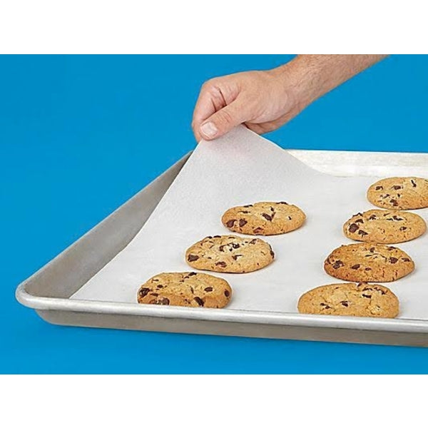 Your Brand microwave oven safe baking paper on sheet pan with chocolate chip cookies being lifted by hand