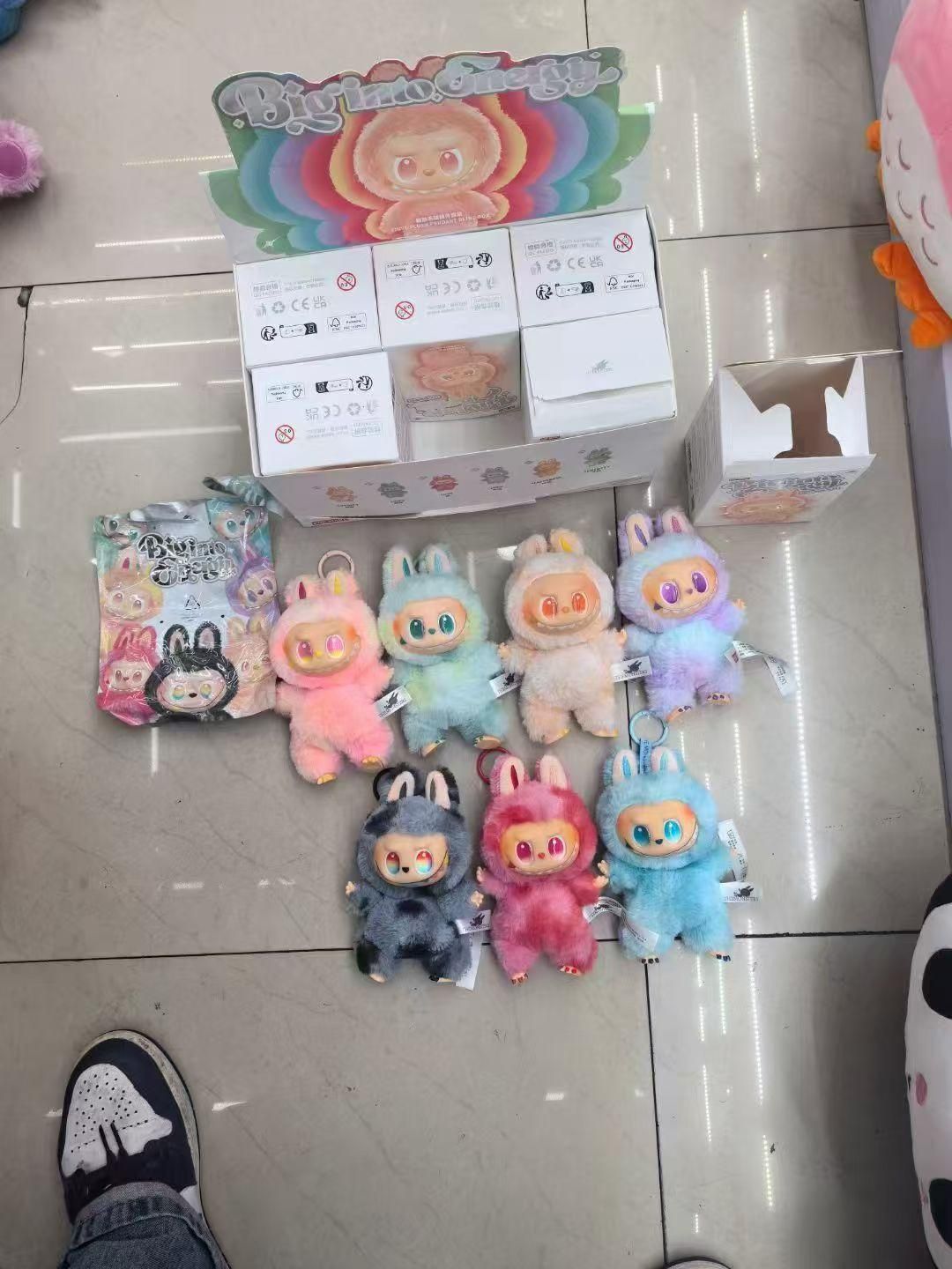 Collection of Labubu plush doll keychains in multiple pastel colors from THE GIR FARMER displayed with packaging boxes