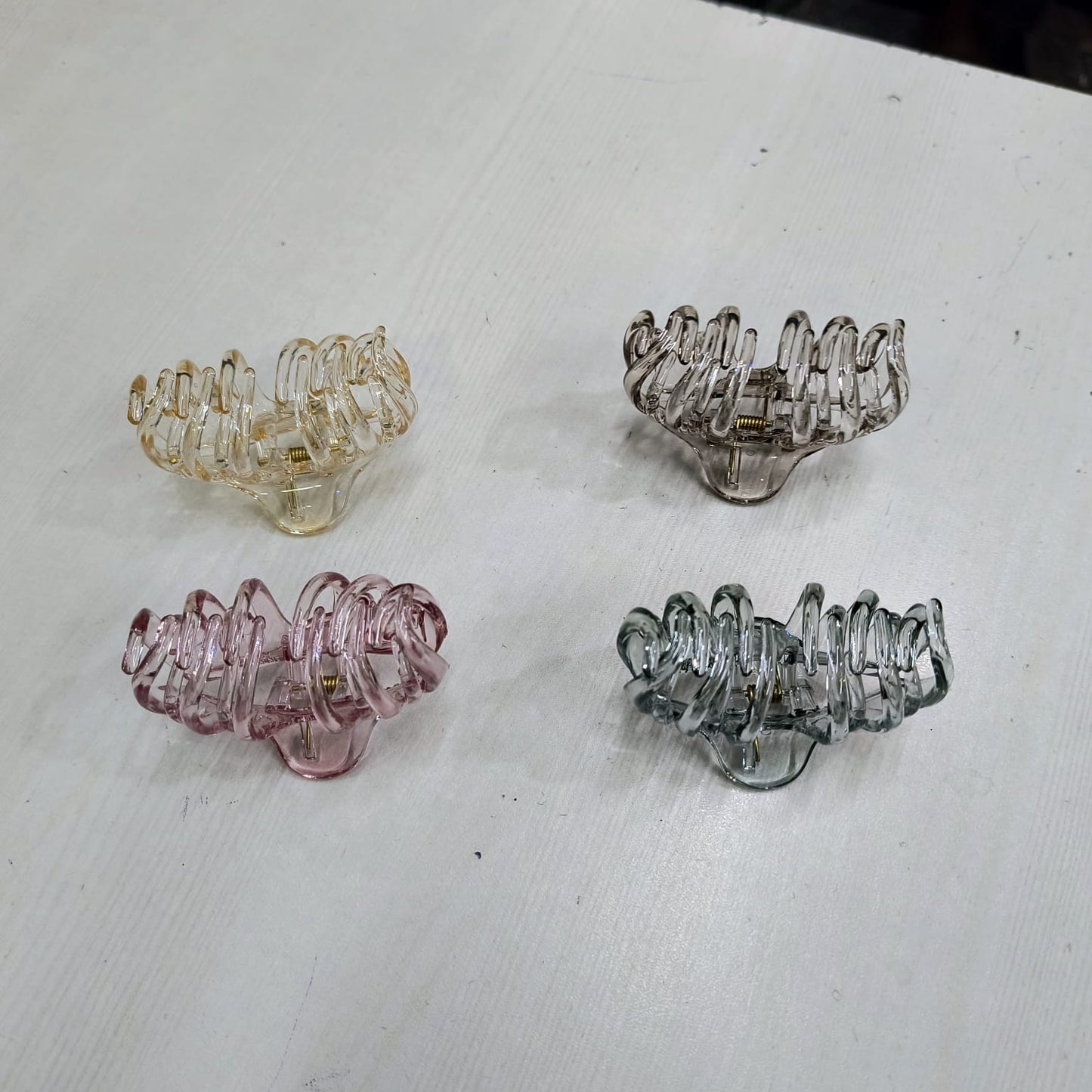 Set of four large claw clip for thick hair in translucent yellow brown pink and gray colors on white surface