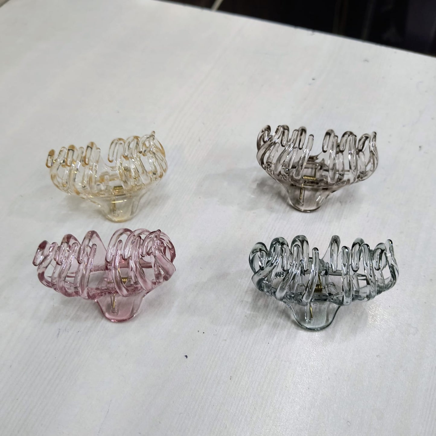 Large claw clip for thick hair in four colors on a white surface