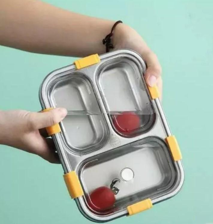 Leak proof multicolor lunch container with three compartments and yellow locks held in hand