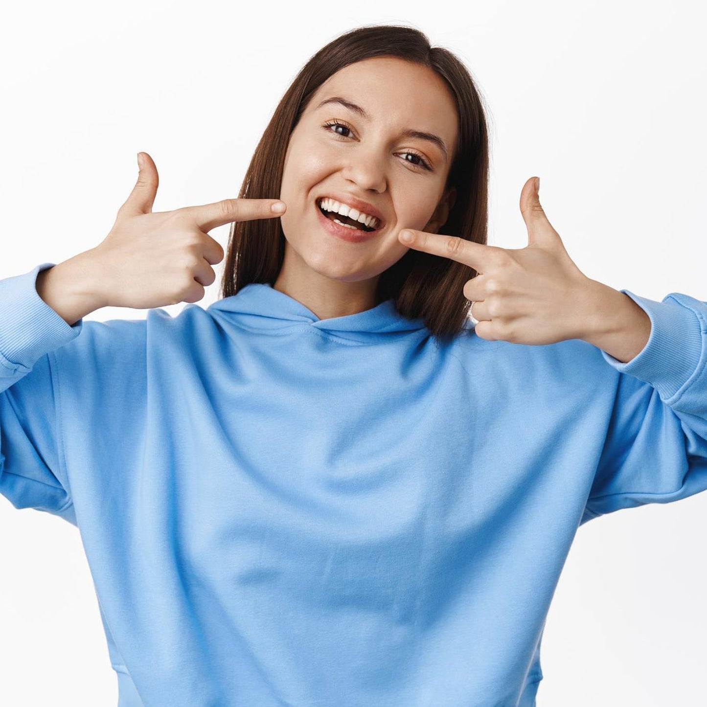 Woman smiling and showing teeth with a six sided soft toothbrush for effective dental care