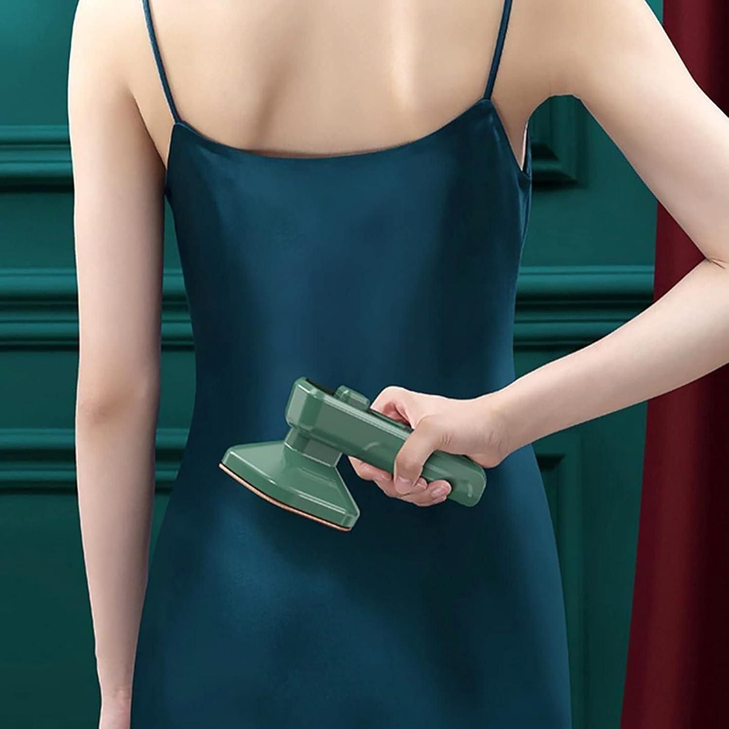Green mini garment steamer for home and travel removing wrinkles from a dark green dress