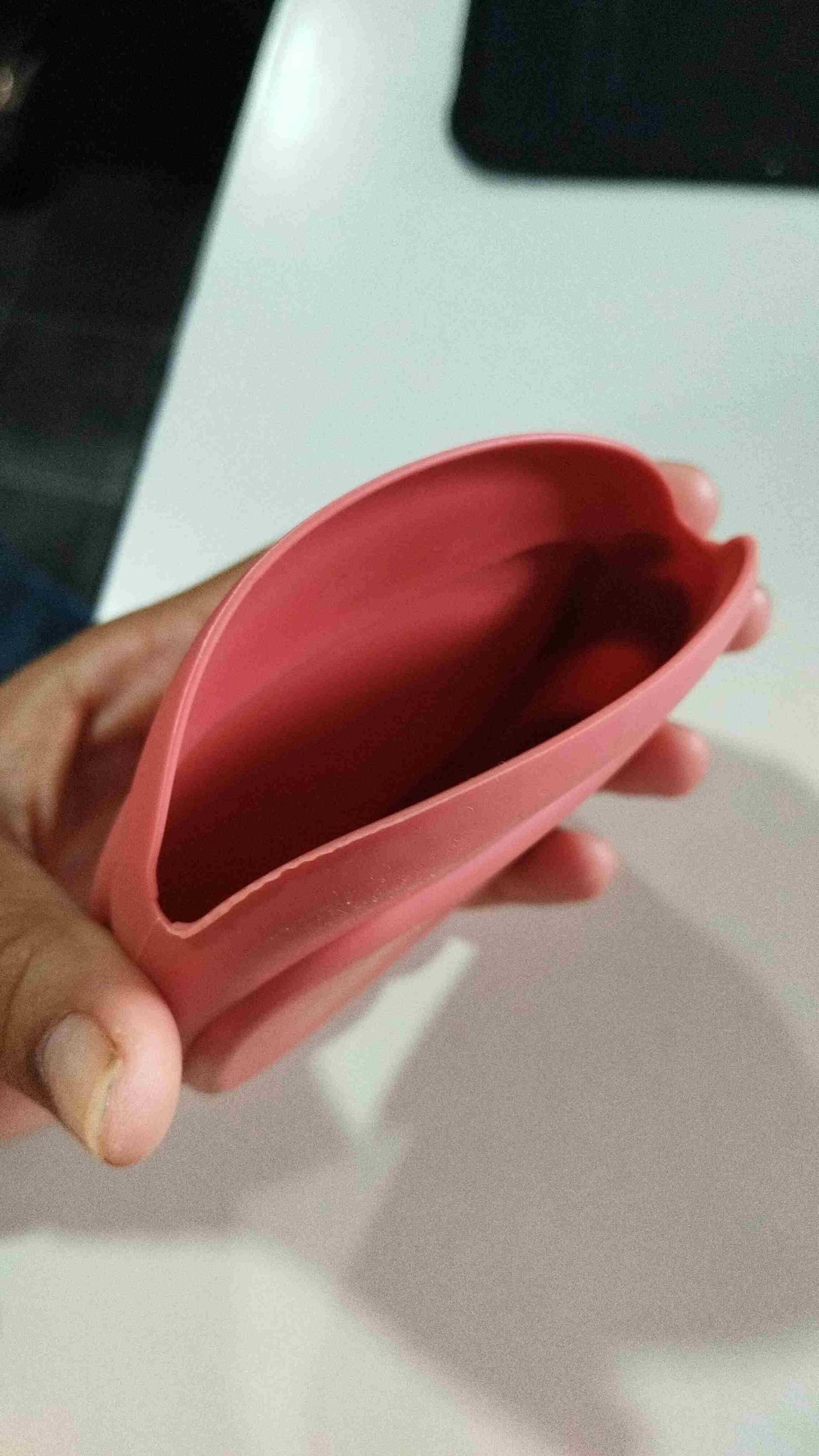 Hand holding a red mini silicone earbud holder from THE GIR FARMER for compact earbud storage